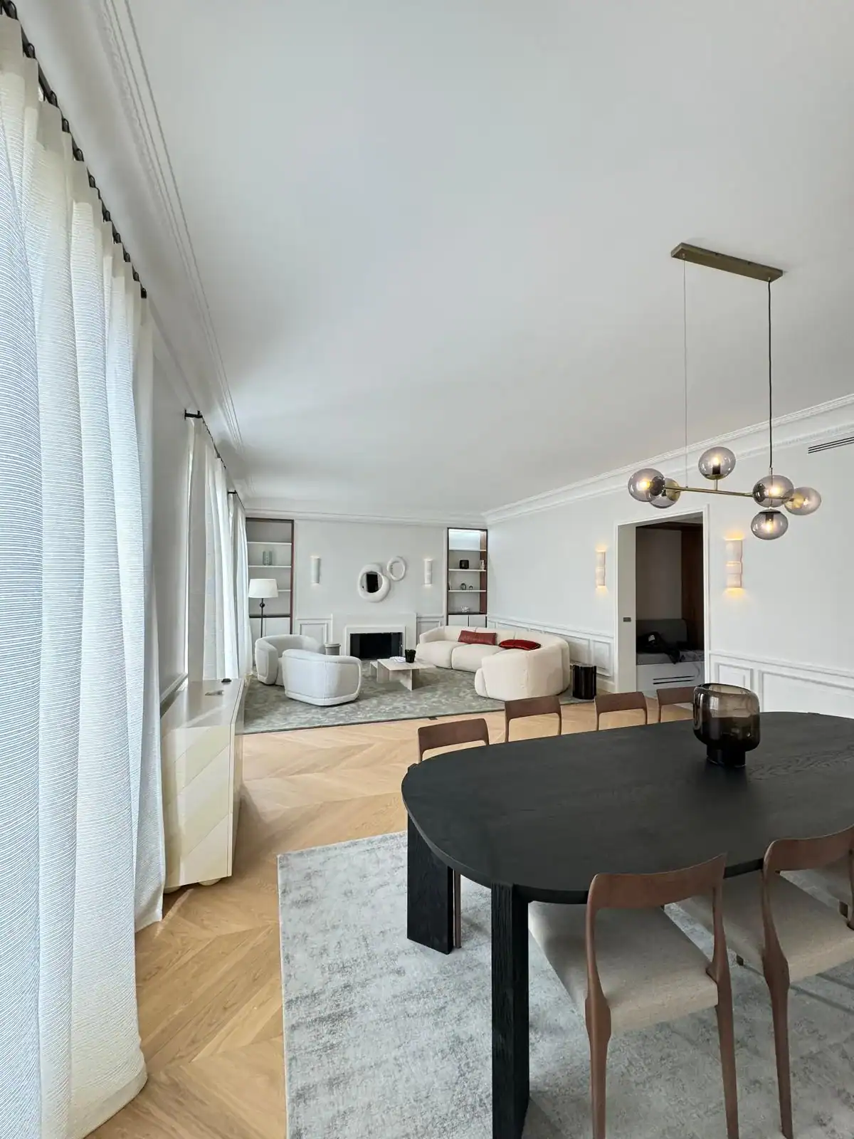 Pièce de vie ouverte avec parquet chevron, table à manger noire et salon contemporain — rénovation Les Artistes Île-de-France